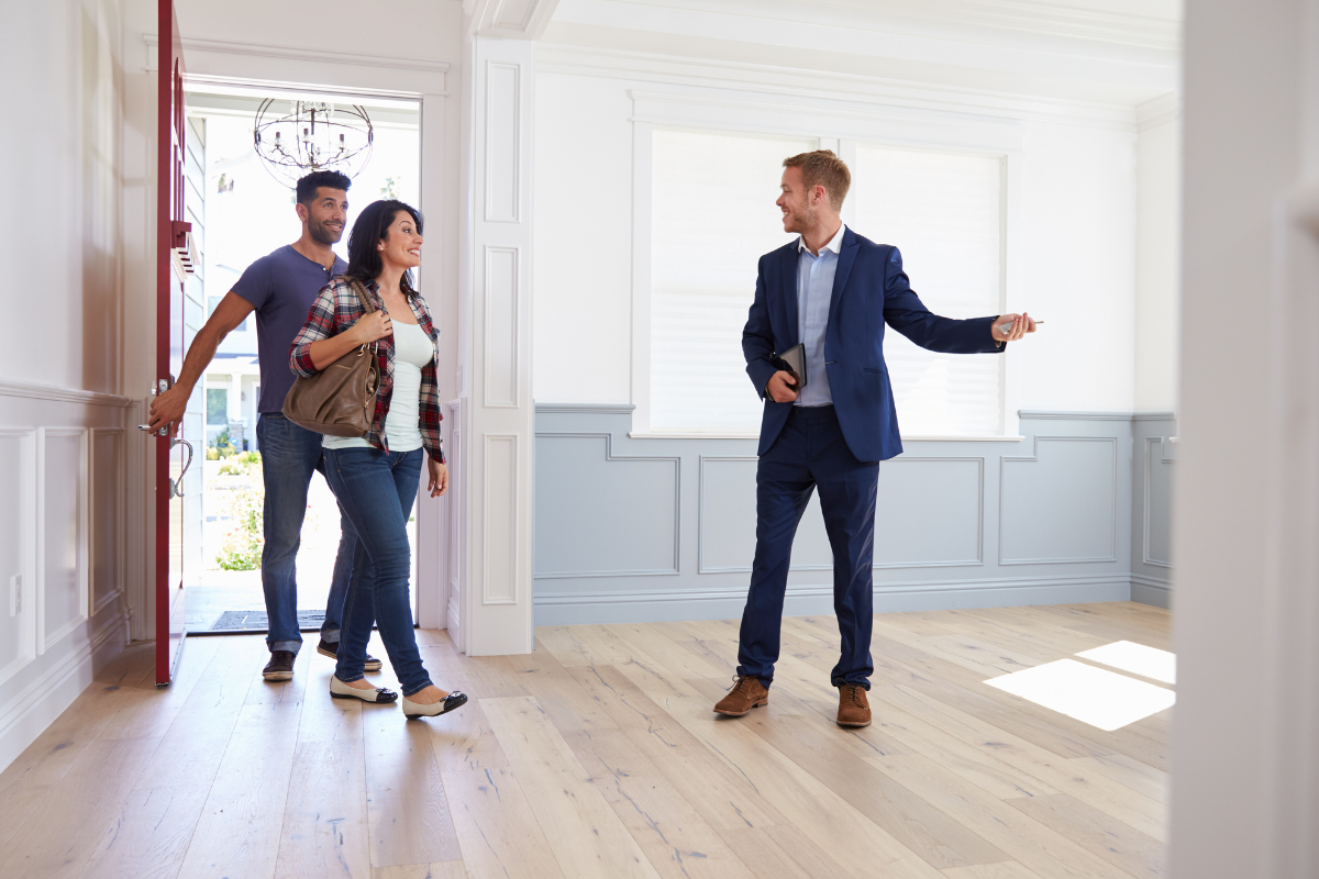 A couple walking into a home with a real estate agent